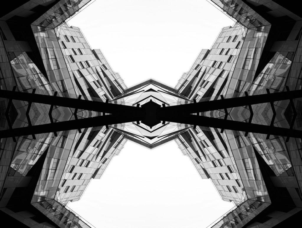 Symmetrical buildings against a bright sky.